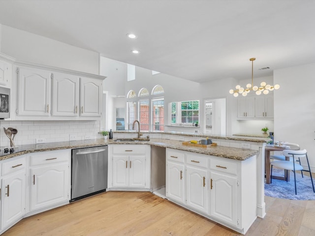 5904 Sandhills Cir, Plano, TX 75093 - kitchen featuring stainless steel appliances, a sink, a peninsula, light wood-style floors, and decorative backsplash