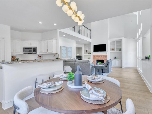 5904 Sandhills Cir, Plano, TX 75093 - dining area featuring a towering ceiling, light wood-type flooring, a brick fireplace, baseboards, and recessed lighting