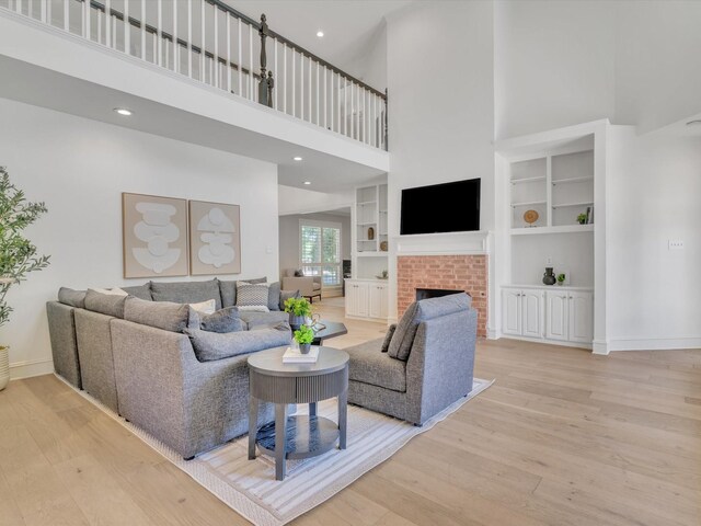 5904 Sandhills Cir, Plano, TX 75093 - living area featuring light wood-style floors, a high ceiling, a brick fireplace, baseboards, and built in features