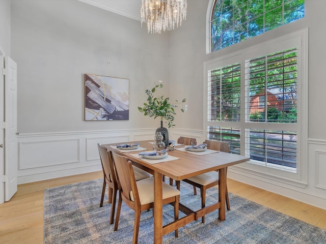 5904 Sandhills Cir, Plano, TX 75093 - dining area with a chandelier, light wood-style flooring, wainscoting, ornamental molding, and a towering ceiling