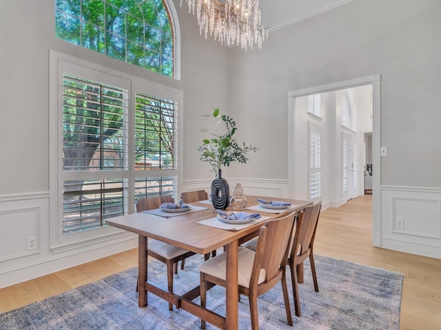 5904 Sandhills Cir, Plano, TX 75093 - dining room with a chandelier, light wood-style flooring, a decorative wall, a wainscoted wall, and crown molding