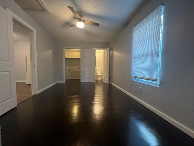 2722 Locust Ave, Dallas, TX 75216 - unfurnished bedroom with baseboards, dark wood-type flooring, freestanding refrigerator, a walk in closet, and a ceiling fan