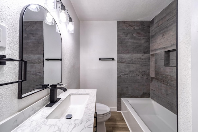 10816 Joaquin Dr, Dallas, TX 75228 - full bathroom with wood finished floors, toilet, a tub, a textured wall, and vanity