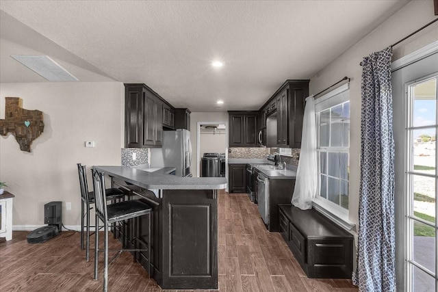 2250 Poolville Cut Off Rd, Poolville, TX 76487 - kitchen featuring stainless steel appliances, a peninsula, tasteful backsplash, washer / clothes dryer, and dark wood-style flooring