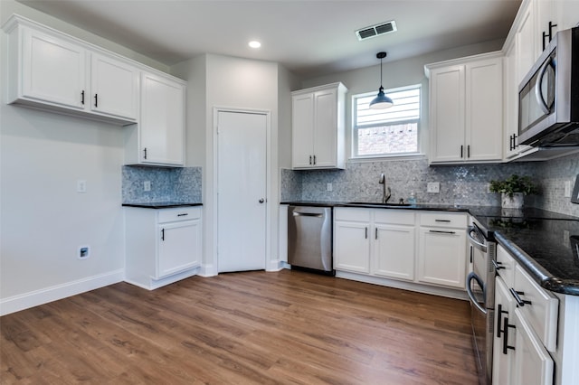 1618 Wildflower Dr, Waxahachie, TX 75165 - kitchen with appliances with stainless steel finishes, a sink, white cabinetry, hanging light fixtures, and decorative backsplash