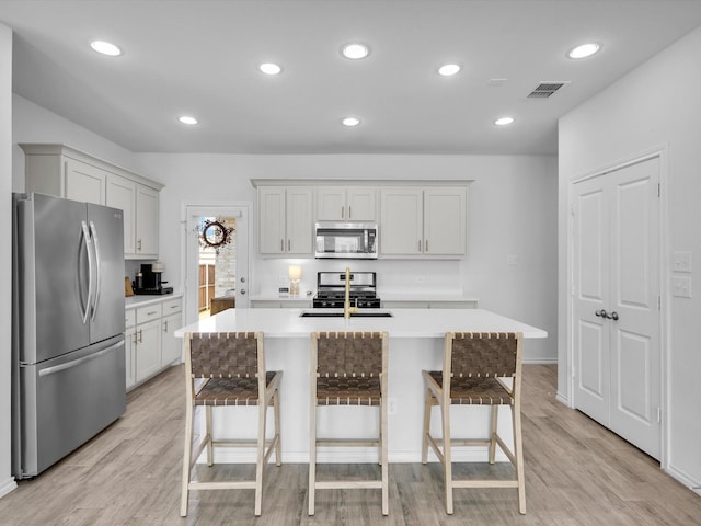 1705 Wayne Ln, Celina, TX 75009 - kitchen with stainless steel appliances, light countertops, a kitchen breakfast bar, light wood-style flooring, and recessed lighting