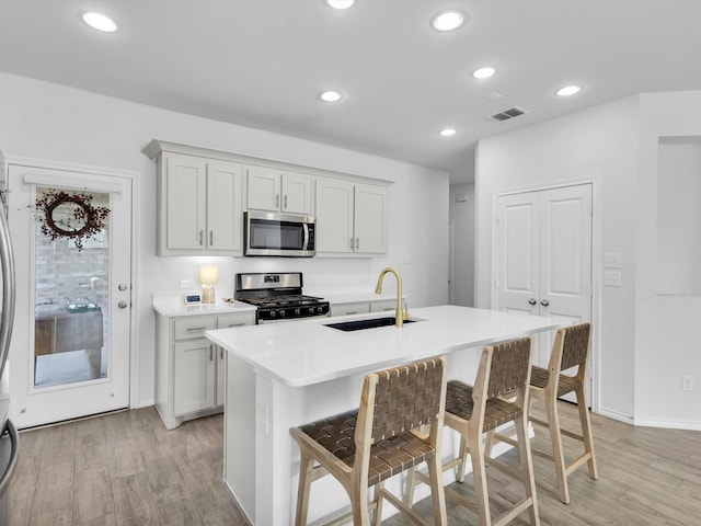 1705 Wayne Ln, Celina, TX 75009 - kitchen featuring appliances with stainless steel finishes, light wood-style floors, a breakfast bar area, a center island with sink, and recessed lighting