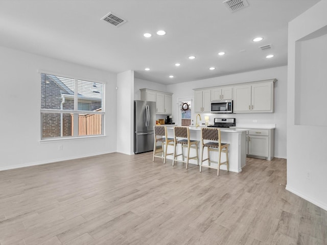 1705 Wayne Ln, Celina, TX 75009 - kitchen featuring stainless steel appliances, recessed lighting, a kitchen bar, healthy amount of natural light, and light wood-type flooring