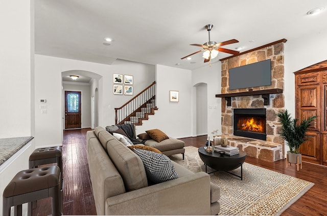 1205 Wynne Dr, Garland, TX 75044 - living room with arched walkways, a stone fireplace, ceiling fan, stairway, and recessed lighting