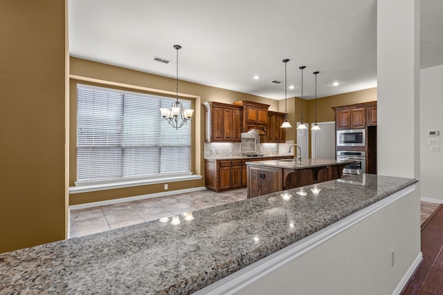 1205 Wynne Dr, Garland, TX 75044 - kitchen featuring stainless steel appliances, baseboards, a sink, a kitchen breakfast bar, and a chandelier