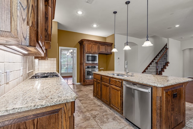 1205 Wynne Dr, Garland, TX 75044 - kitchen with stainless steel appliances, a sink, decorative backsplash, an island with sink, and brown cabinets