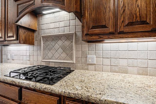 1205 Wynne Dr, Garland, TX 75044 - kitchen with black gas cooktop, decorative backsplash, light stone countertops, and dark brown cabinets
