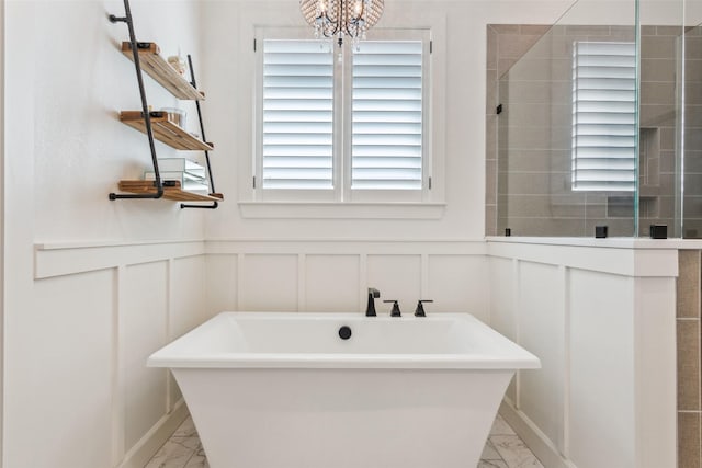 10136 Braided Briar Ln, Waco, TX 76712 - bathroom featuring marble look tile flooring, a decorative wall, a soaking tub, healthy amount of natural light, and wainscoting