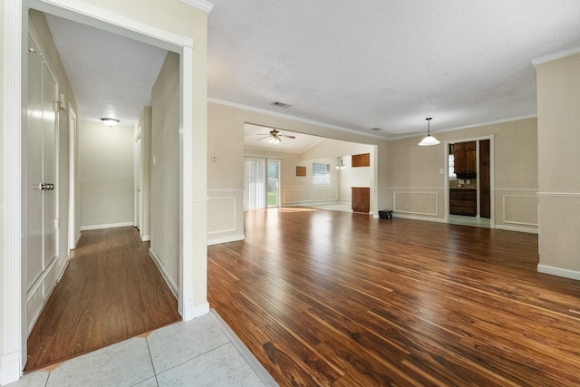 908 Cherry Laurel Ln, Arlington, TX 76012 - unfurnished living room featuring crown molding, wood finished floors, ceiling fan, a textured ceiling, and a decorative wall