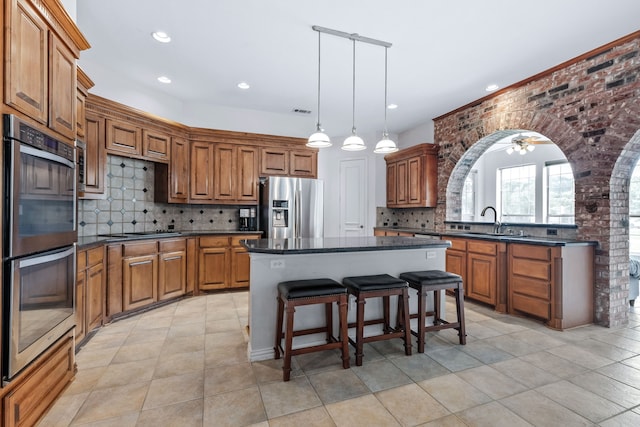 420 Bee Caves Rd, Lucas, TX 75002 - kitchen featuring stainless steel appliances, brown cabinets, dark countertops, tasteful backsplash, and recessed lighting