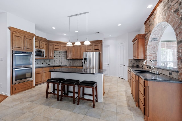 420 Bee Caves Rd, Lucas, TX 75002 - kitchen featuring appliances with stainless steel finishes, a sink, backsplash, a breakfast bar, and brown cabinets