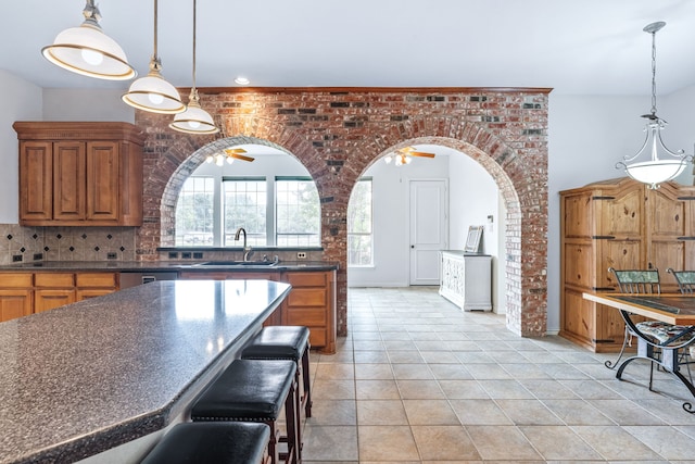 420 Bee Caves Rd, Lucas, TX 75002 - kitchen with a sink, dark countertops, light tile patterned flooring, tasteful backsplash, and brown cabinets