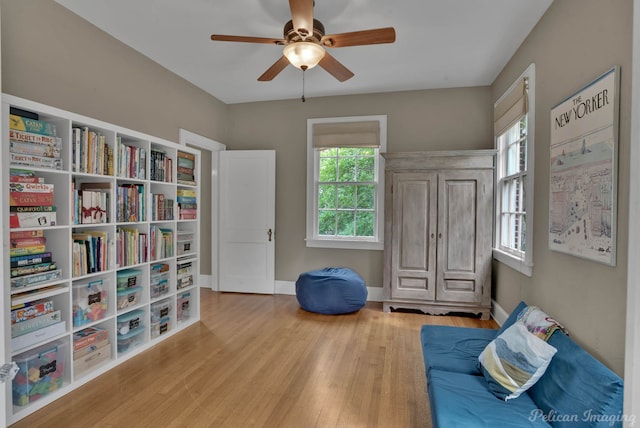 sitting room featuring ceiling fan, wood finished floors, and baseboards