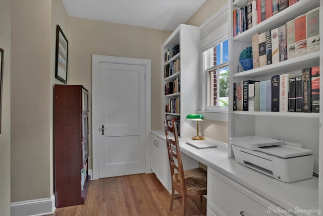 home office with light wood finished floors and built in study area