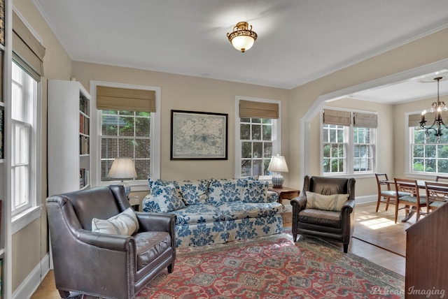 living room with a chandelier, baseboards, wood finished floors, and crown molding