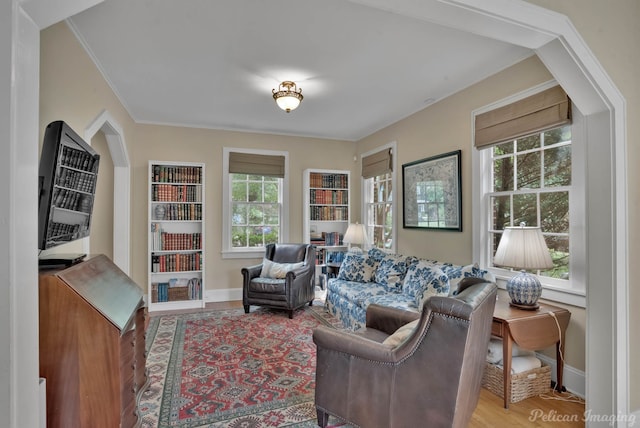 living area with baseboards, crown molding, and wood finished floors