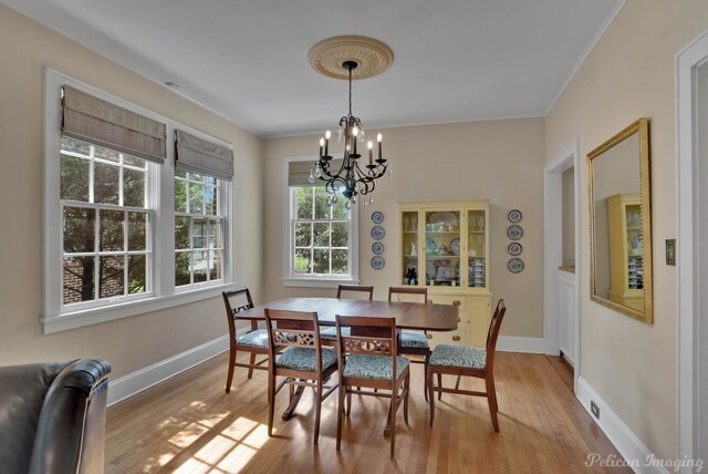 dining room featuring a chandelier, light wood-style floors, ornamental molding, and baseboards