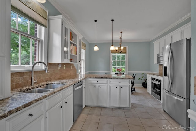 kitchen featuring appliances with stainless steel finishes, a sink, a peninsula, white cabinetry, and tasteful backsplash