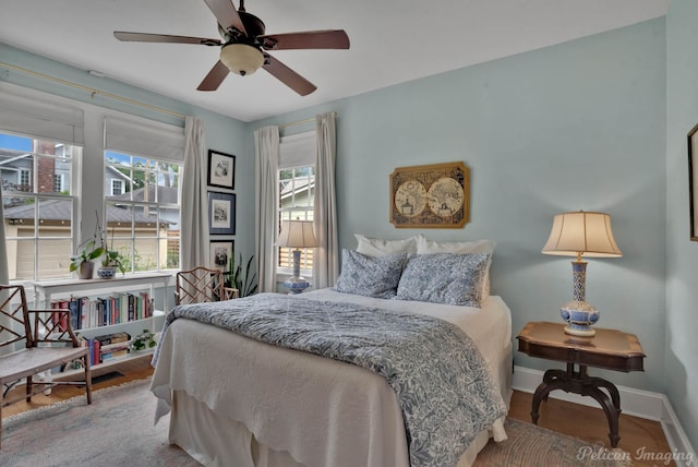 bedroom featuring multiple windows, wood finished floors, baseboards, and a ceiling fan
