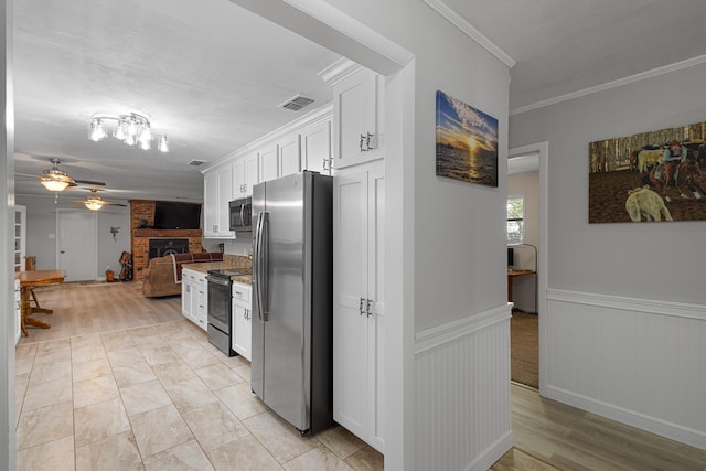 818 Country Club Rd, Bowie, TX 76230 - kitchen with stainless steel appliances, white cabinets, a fireplace, crown molding, and ceiling fan