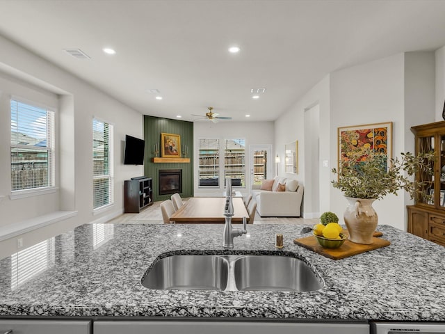 571 Mckenna Dr, Fate, TX 75087 - kitchen with a fireplace, open floor plan, a sink, recessed lighting, and stone counters