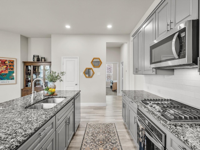 571 Mckenna Dr, Fate, TX 75087 - kitchen with appliances with stainless steel finishes, a sink, gray cabinets, dark stone countertops, and recessed lighting