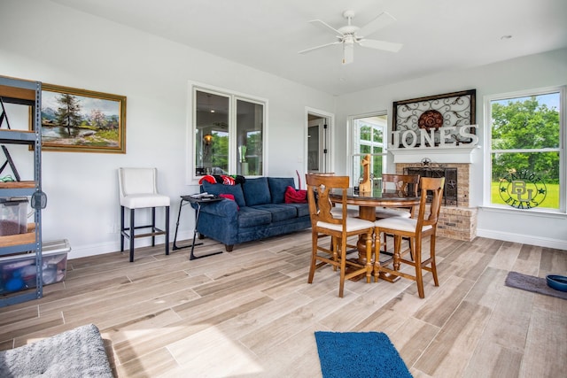 6170 Green Meadow Ln, Terrell, TX 75160 - dining room featuring a ceiling fan, light wood-type flooring, a brick fireplace, and baseboards