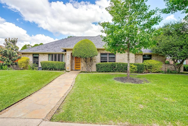 view of front of house with brick siding, a front yard, and a shingled roof