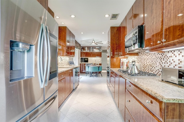 kitchen featuring appliances with stainless steel finishes, brown cabinetry, ceiling fan, a sink, and recessed lighting