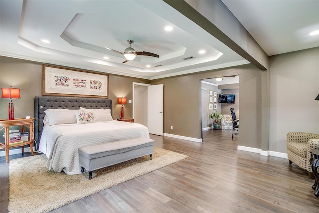 bedroom featuring a raised ceiling, baseboards, recessed lighting, and wood finished floors
