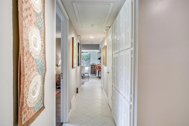 hall featuring attic access and baseboards