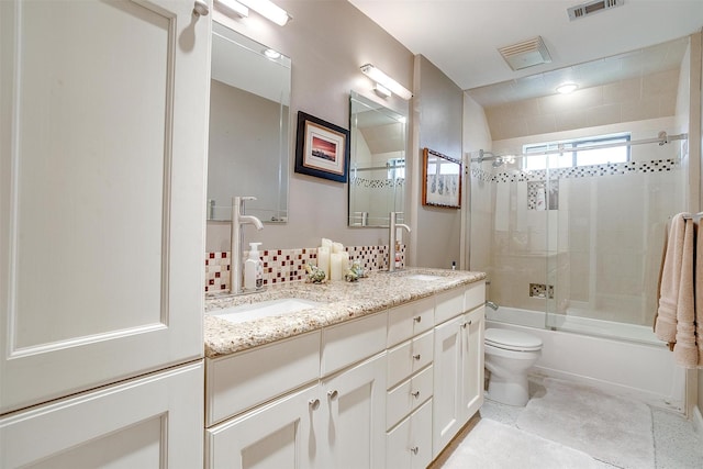 bathroom with double vanity, toilet, shower / bath combination with glass door, and backsplash
