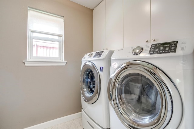 clothes washing area with washer and dryer, baseboards, and cabinet space