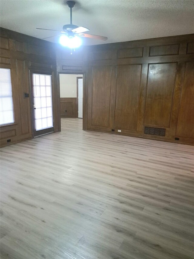 327 Trevino Trl, Lancaster, TX 75146 - unfurnished living room with light wood-style flooring, a ceiling fan, a textured ceiling, and wooden walls