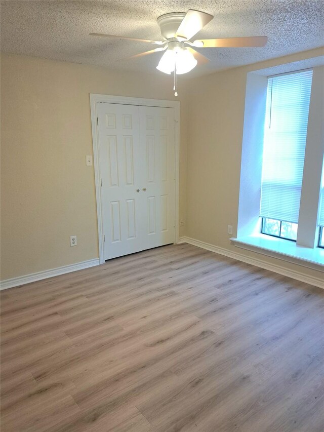 327 Trevino Trl, Lancaster, TX 75146 - unfurnished bedroom featuring light wood-style floors, baseboards, a textured ceiling, a closet, and ceiling fan