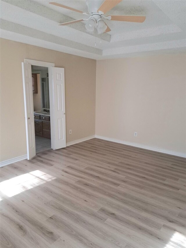 327 Trevino Trl, Lancaster, TX 75146 - empty room with a ceiling fan, a tray ceiling, light wood finished floors, and baseboards