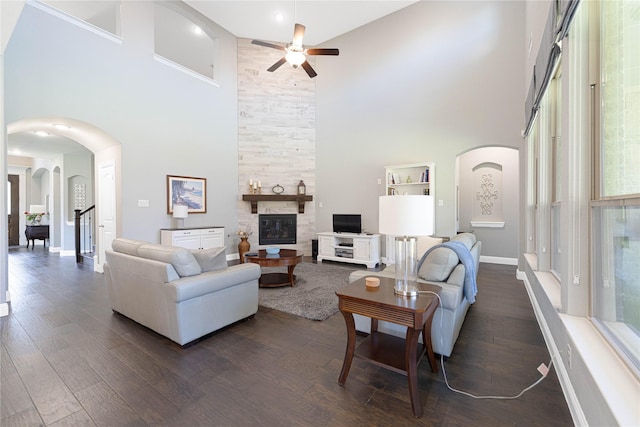 331 Sagemeadow Rd, Wylie, TX 75098 - living area featuring a high ceiling, arched walkways, a ceiling fan, a stone fireplace, and dark wood-type flooring