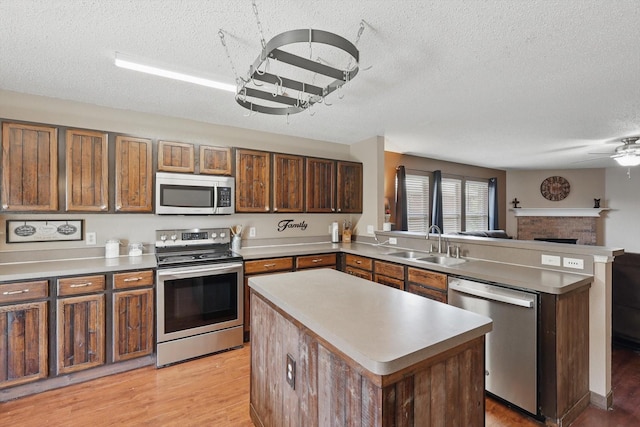1554 Brandywine Ln, Little Elm, TX 75068 - kitchen featuring stainless steel appliances, a textured ceiling, a sink, a peninsula, and open floor plan