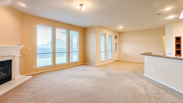 10252 Red Bluff Ln, Fort Worth, TX 76177 - unfurnished living room with light carpet, a glass covered fireplace, recessed lighting, and light tile patterned floors