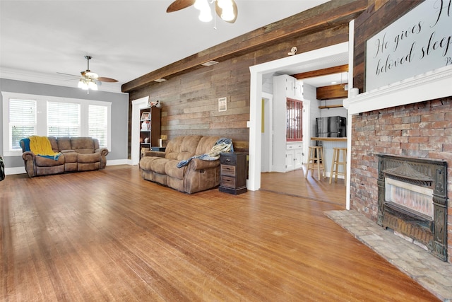 820 W Gandy St, Denison, TX 75020 - living area featuring ceiling fan, wood finished floors, wooden walls, a brick fireplace, and baseboards