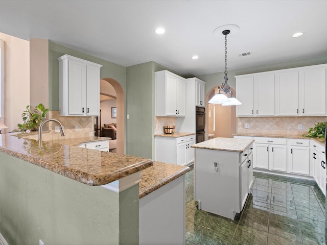 2105 Indian Trl, Rowlett, TX 75088 - kitchen with arched walkways, tasteful backsplash, a peninsula, and recessed lighting