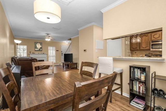 14333 Preston Rd Unit 2403, Dallas, TX 75254 - dining room with ornamental molding, a fireplace, light wood-type flooring, ceiling fan, and stairway