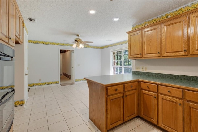 607 Dogwood Cir, Powderly, TX 75473 - kitchen featuring a textured ceiling, brown cabinetry, ceiling fan, a peninsula, and light tile patterned floors