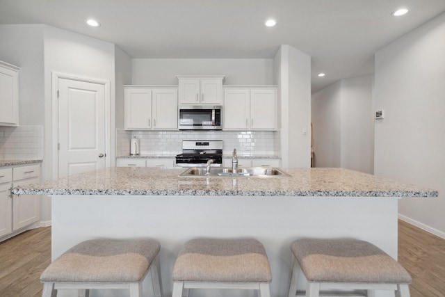 8580 Big Apple Dr, Fort Worth, TX 76179 - kitchen with appliances with stainless steel finishes, a sink, light wood-type flooring, an island with sink, and recessed lighting