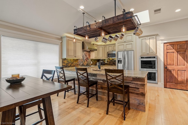 118 Lightning Trl, Forney, TX 75126 - kitchen featuring stainless steel appliances, cream cabinetry, wall chimney exhaust hood, backsplash, and light stone countertops